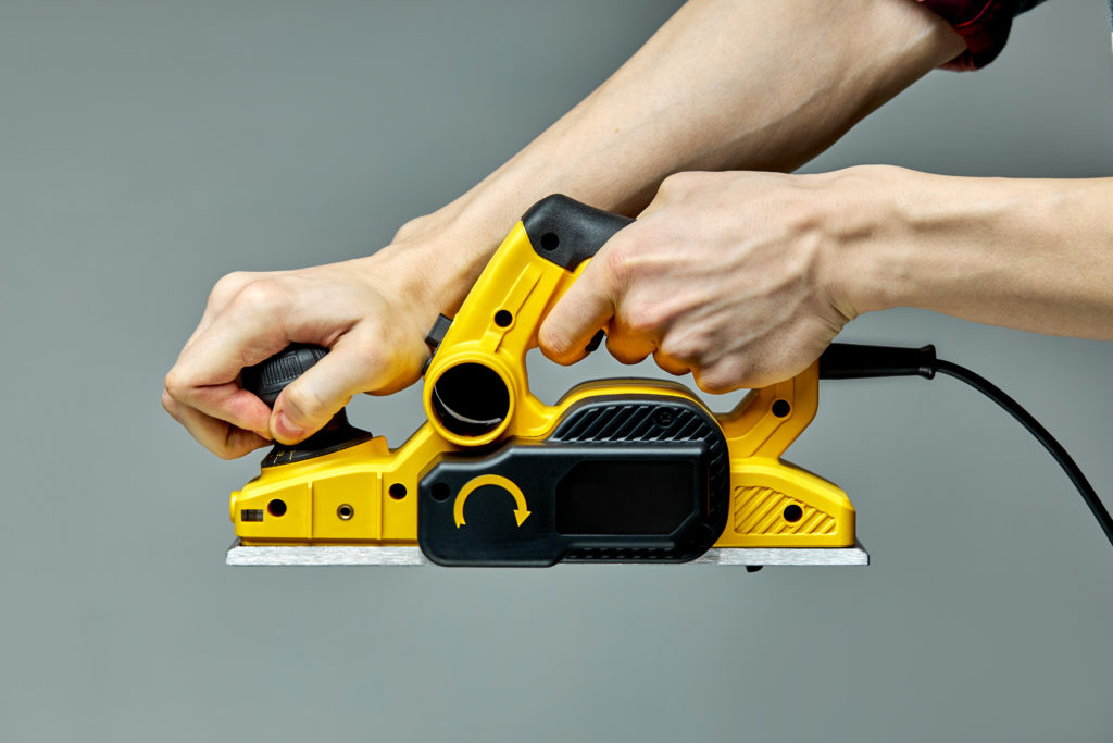 Carpenter hands turn on electric planer jointer